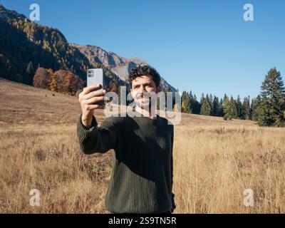 Handsome man taking selfies with beautiful landscape of the mountains behind him - Traveling and technology. Autumn season. Stock Photo