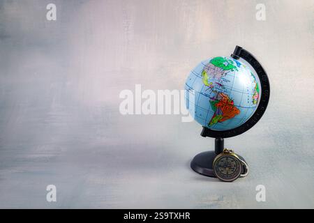 Globe Highlighting the Americas with Compass on Textured Gray Background Stock Photo