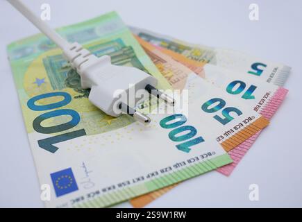 Electric power cable plug lies on a stack of money. Euro cash banknotes. The concept of increasing prices for electricity. Stock Photo