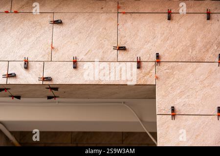 Tile leveling system with plastic clips and wedges, shot while the tile mortar sets. Wall tiling. Stock Photo
