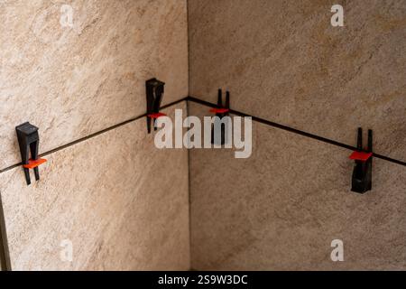 Tile leveling system with plastic clips and wedges, shot while the tile mortar sets. Wall tiling. Stock Photo