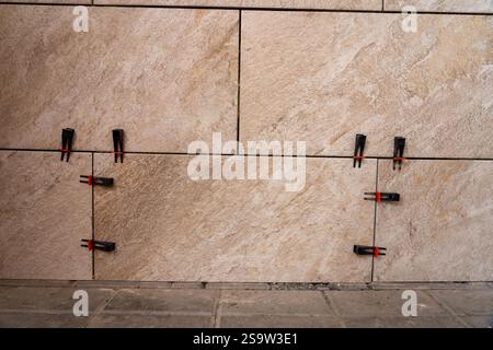 Tile leveling system with plastic clips and wedges, shot while the tile mortar sets. Wall tiling. Stock Photo