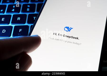 DeepSeek AI chat and Deep seeek logo is seen on the smartphone placed on laptop keyboard and finger pointing at it. Concept for a new chat bot, compet Stock Photo