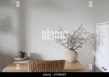 Spring interior still life. Elegant home office composition. up of coffee, tea on old books. Blooming cherry plum tree branches in textured vase Stock Photo