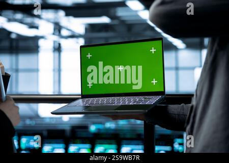 Engineers in data center using green screen laptop, implementing predictive analytics scripts, reviewing equipment health, adjusting system parameters, coordinating maintenance tasks Stock Photo