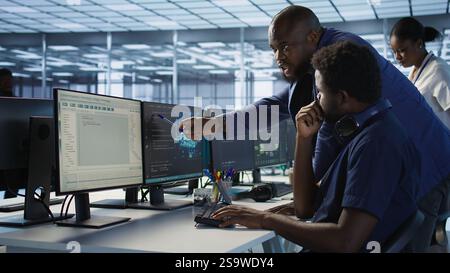 Data center manager helps intern implement AI predictive maintenance systems. Server farm supervisor checks work done by employee using artificial intelligence to identify hardware failures, camera A Stock Photo