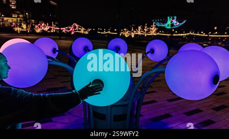 A visitor touches the interactive "In Bloom" installation at the Battersea Power Station Light Festival. Stock Photo