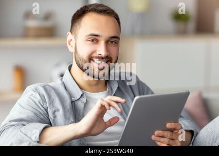 Online life concept. Happy young man using tablet computer, working or studying from home Stock Photo