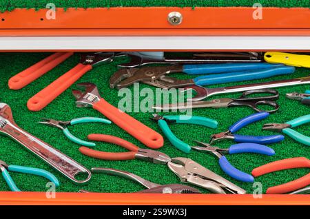 Assorted pliers wrench clamping tools displayed in open toolbox drawer. Stock Photo