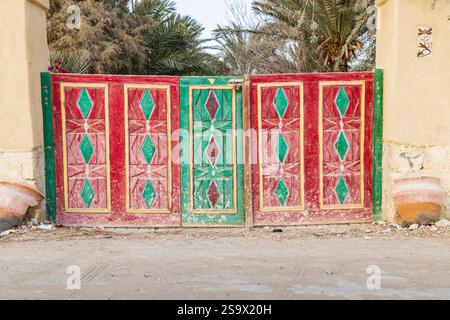 Faiyum, Egypt. Red and green painted wooden gate in a wall. Stock Photo
