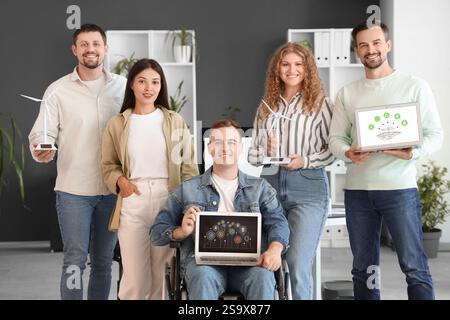 Colleagues with laptops and wind turbine models in office. Green energy concept Stock Photo