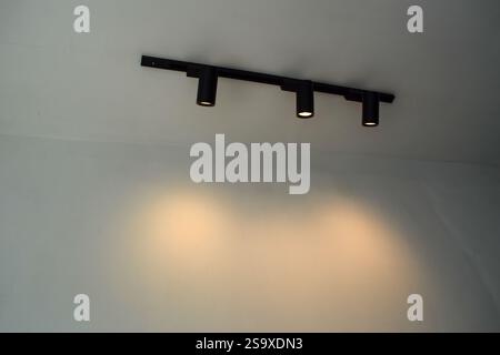 Spotlights under the ceiling on the wall. LED track lighting system. Black interior spotlights Stock Photo