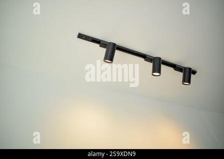 Spotlights under the ceiling on the wall. LED track lighting system. Black interior spotlights Stock Photo