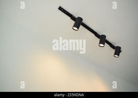 Spotlights under the ceiling on the wall. LED track lighting system. Black interior spotlights Stock Photo
