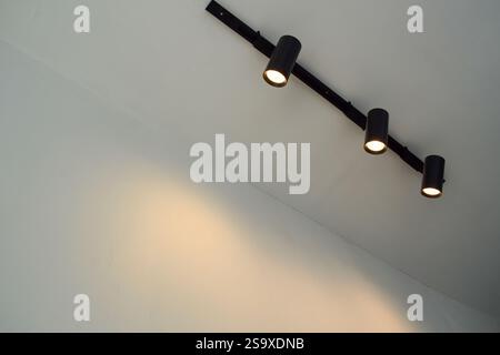 Spotlights under the ceiling on the wall. LED track lighting system. Black interior spotlights Stock Photo