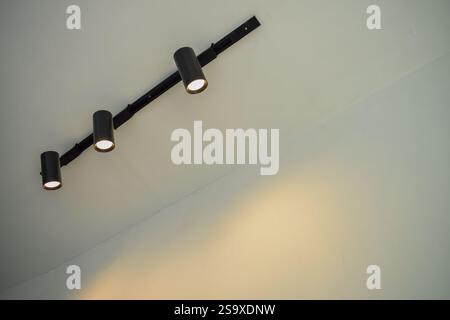 Spotlights under the ceiling on the wall. LED track lighting system. Black interior spotlights Stock Photo