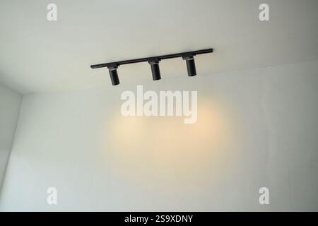 Spotlights under the ceiling on the wall. LED track lighting system. Black interior spotlights Stock Photo