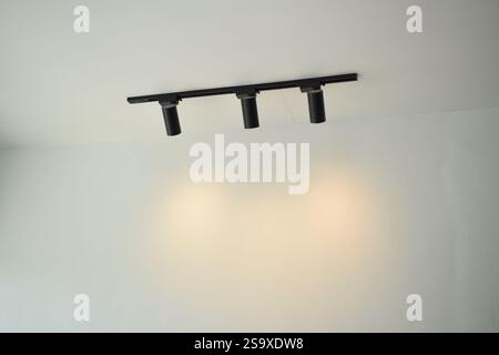 Spotlights under the ceiling on the wall. LED track lighting system. Black interior spotlights Stock Photo