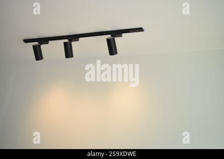 Spotlights under the ceiling on the wall. LED track lighting system. Black interior spotlights Stock Photo