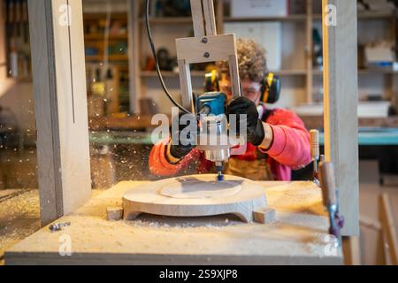 Carpentry workshop craftsman master working. Manual wood milling guy holds tool controlling process Stock Photo