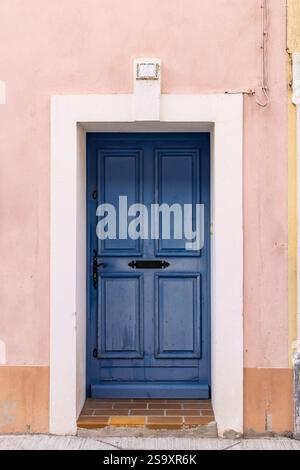 Aigues-Mortes, Gard, Occitania, France. Blue painted door in a pink stucco wall. Stock Photo