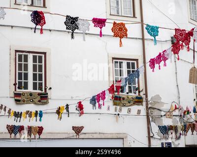Colorful crocheted doilies hanging over the street. Stock Photo