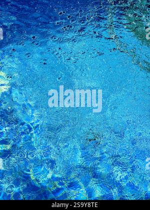 Vibrant Blue Pool Water with Ripples  A close-up of the edge of a swimming pool showcasing vibrant blue water with ripples and patterns formed by wate Stock Photo