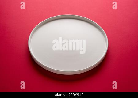 Top view of empty ceramic white plate on red background Stock Photo
