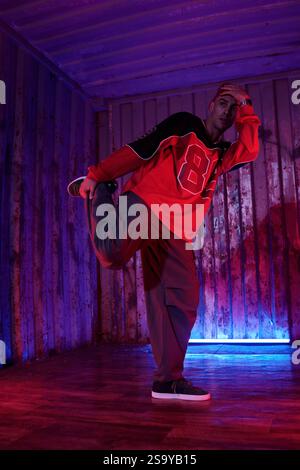 Performing Dance Pose in Front of Illuminated Wall Stock Photo