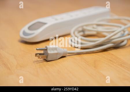 4 outlets portable power extension board on wooden background. Selective focus on plug. Stock Photo