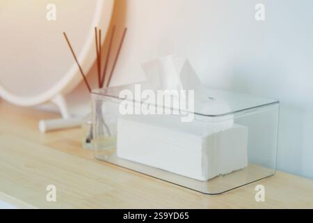 Selective focus of clear plastic box with napkin and mirror, reed diffuser on wooden table in room Stock Photo
