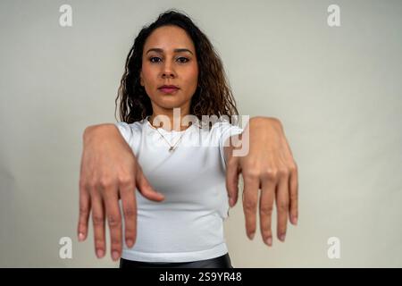 Young latin woman performing a zombie dance move with outstretched arms and a serious expression Stock Photo