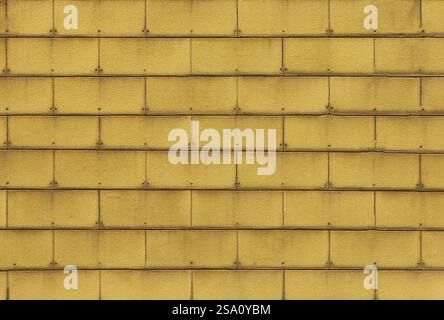 Yellow wall tiles creating repeating pattern with rivets Stock Photo