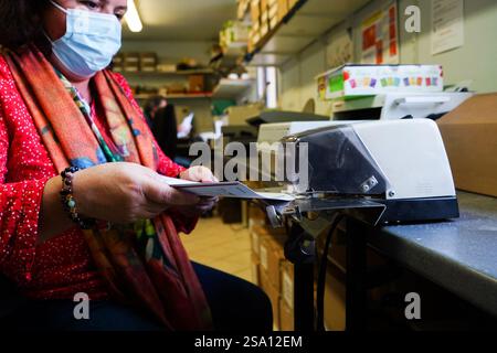 Disabled worker working in the printing, reprography and marking workshop. Binding with electric stapler. Stock Photo
