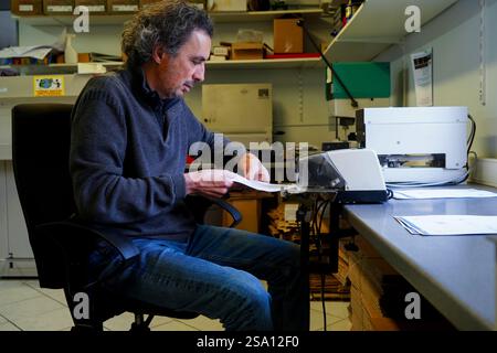 Disabled worker working in the printing, reprography and marking workshop. Binding with electric stapler. Stock Photo