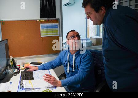 Disabled worker and his monitor working in the printing, reprography and marking workshop. Stock Photo