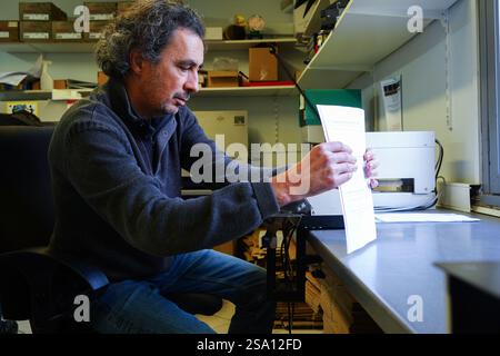 Disabled worker working in the printing, reprography and marking workshop. Binding with electric stapler. Stock Photo