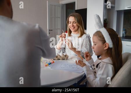 Family painting Easter decorations together at home with joy and creativity Stock Photo