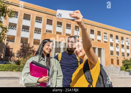 Frontal view of three male and females multi-ethnic university students taking selfie in the campus Stock Photo