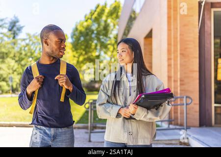 Multi-ethnic african and chinese exchange students talking walking along university campus Stock Photo
