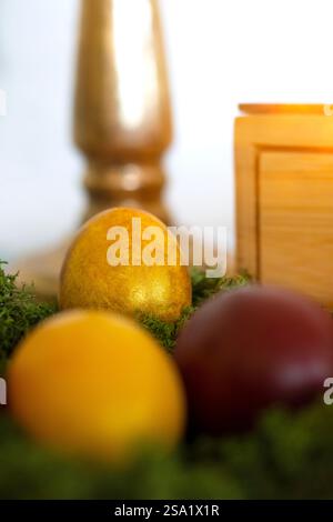 Closeup of yellow and red Easter eggs on green moss, golden egg standing out Stock Photo