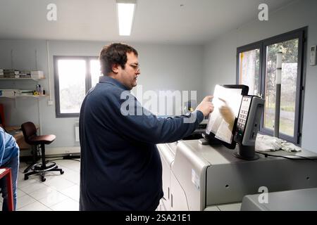 Disabled worker working in the printing, reprography and marking workshop. Programming the printer before printing. work with disabilities 016794 034 Stock Photo