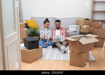 couple, boxes in new home, use laptop for interior design choices, online shopping Stock Photo