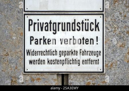 Stuttgart, Baden-Württemberg, Germany - January 23, 2025: Sign with the inscription: Privatgrundstück - Parken verboten on a wall in Stuttgart. The sign warns that illegally parked vehicles must be removed for a fee *** Schild mit der Aufschrift: Privatgrundstück Parken verboten an einer Wand in Stuttgart. Das Schild warnt davor, widerrechtlich abgestellte Fahrzeuge kostenpflichtig zu entfernen Stock Photo