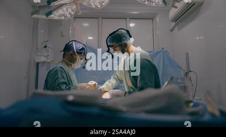 Team of two doctors men surgeons processing surgical operation using endoscopic medical instruments in sterile operating room hospital emergency Stock Photo