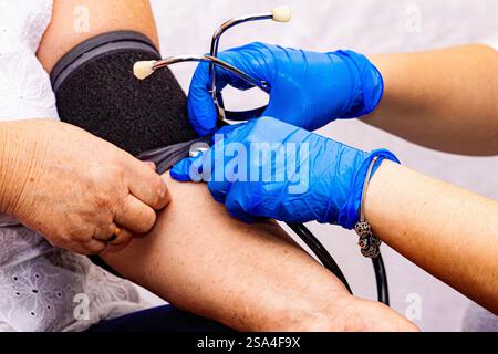 Doctor using sphygmomanometer with stethoscope checking blood pressure ...