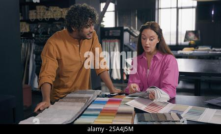Diverse fashion designers Arabian man Caucasian woman couple customers choosing fabric samples talk discuss interior design salesman help to choose Stock Photo