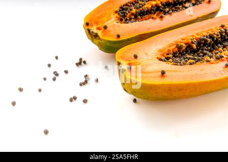 Side view of two halves of a cut papaya showing the yellow orange colour flesh and black seeds isolated on white. Stock Photo