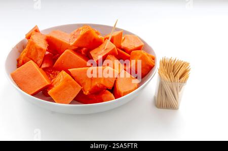 Sweet soft cut pieces of ripe papaya served on a plate with wooden picks isolated on white. Stock Photo