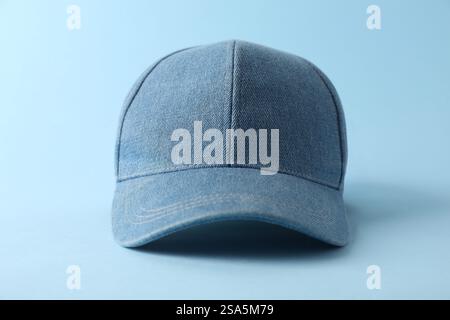 Stylish denim baseball cap on light blue background, closeup. Mockup for design Stock Photo